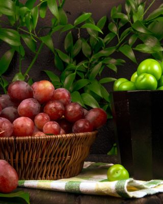 side-view-fresh-sweet-grape-wicker-basket-bowl-with-sour-green-plums-wooden-surface-green-leaves-table